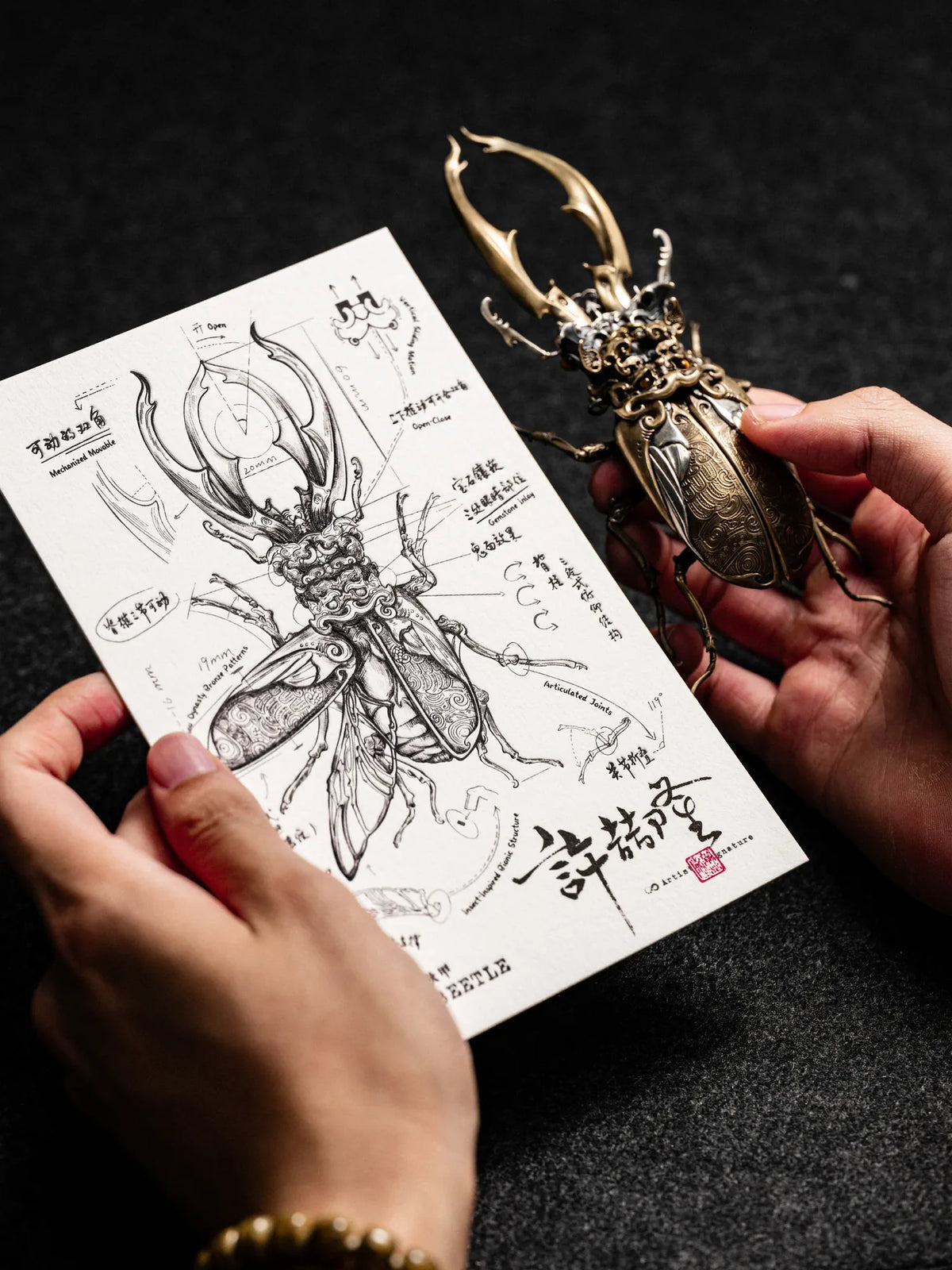 The finished Ghostface Beetle sculpture beside a design drawing signed by Xu Zhelong