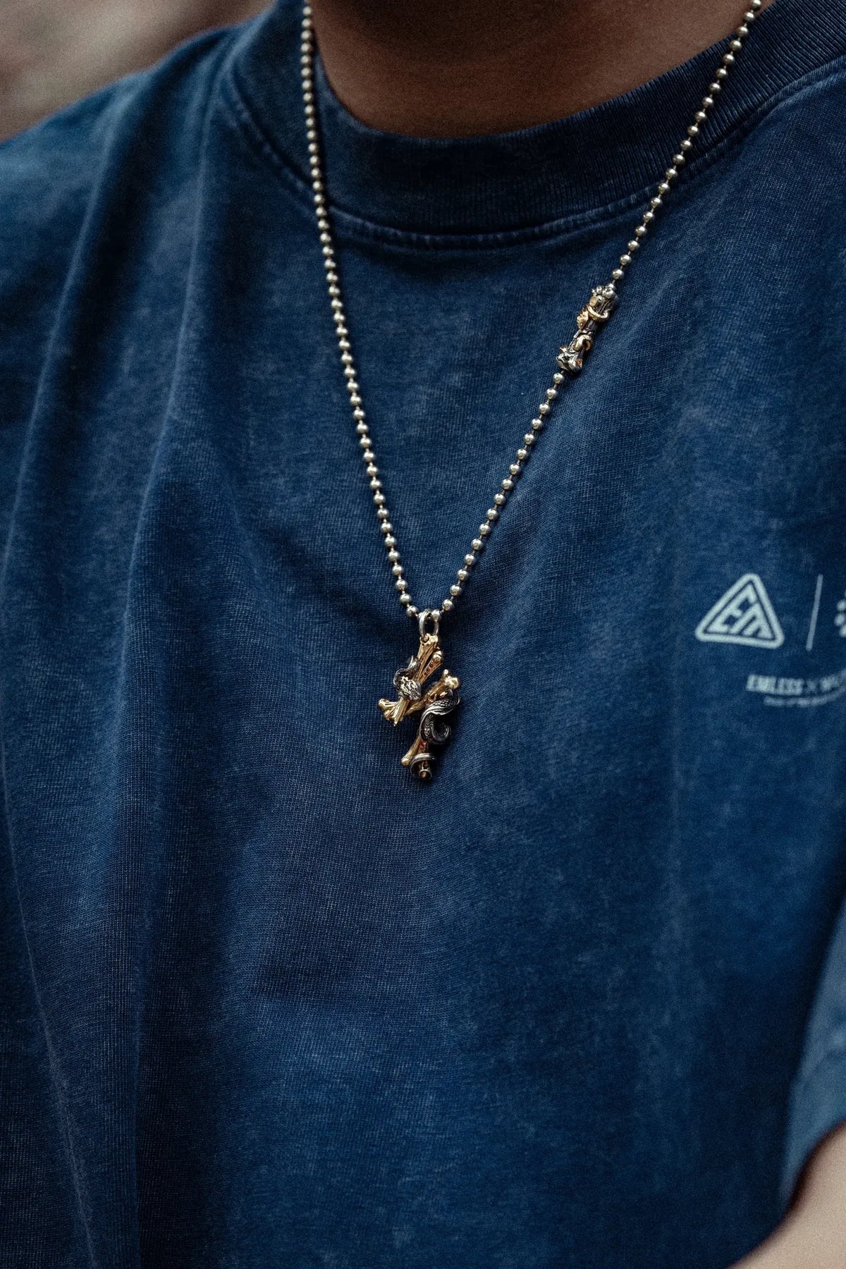 A model wears a Serpent Lightning Bone pendant with the blue collaboration T-shirt
