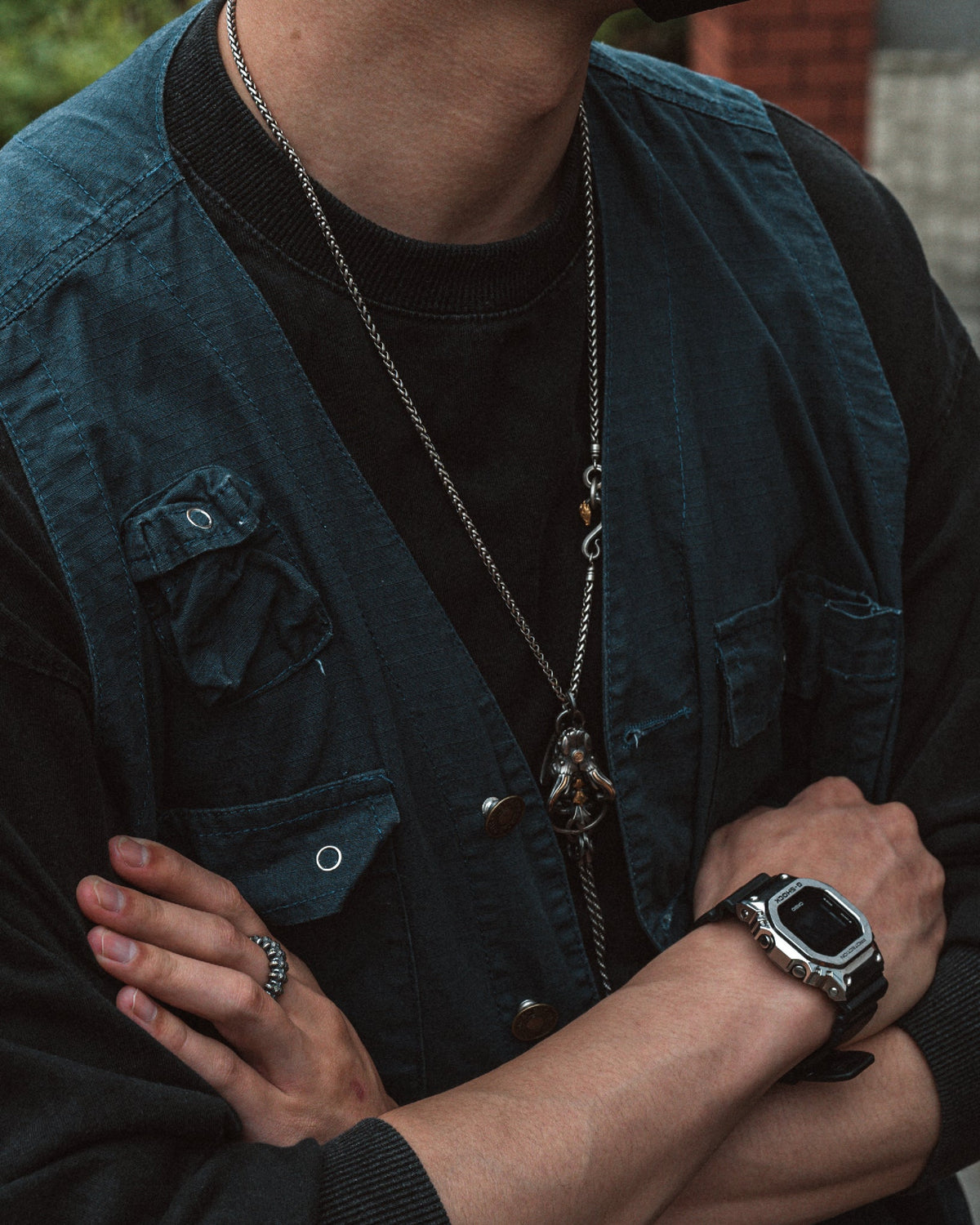Immortal Skeleton amulet worn on a long chain over a dark shirt and blue vest