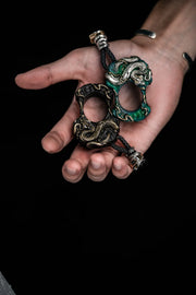 Black and green Vine Serpent knuckle accessories displayed in the palm of a hand