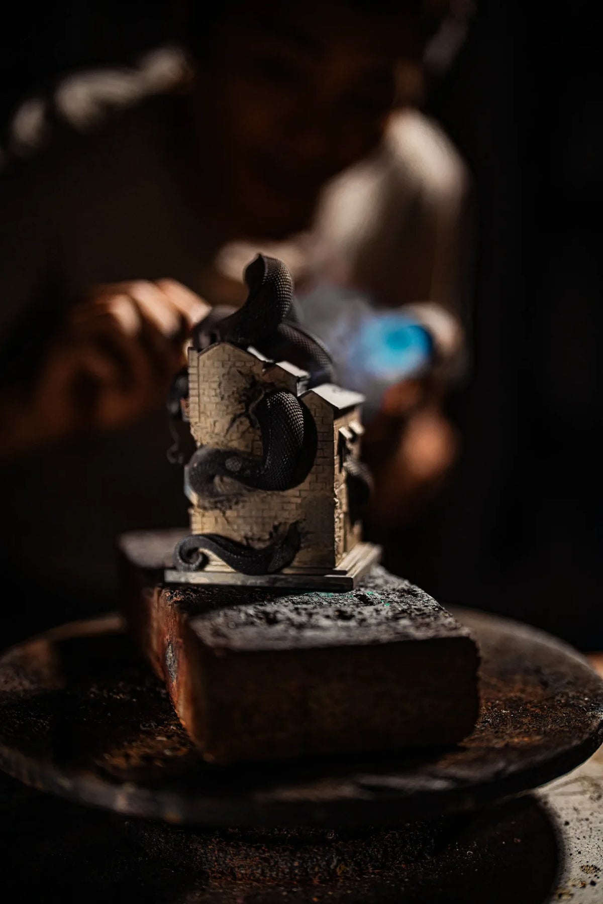An artisan applies a flame while working on the metal serpent house sculpture