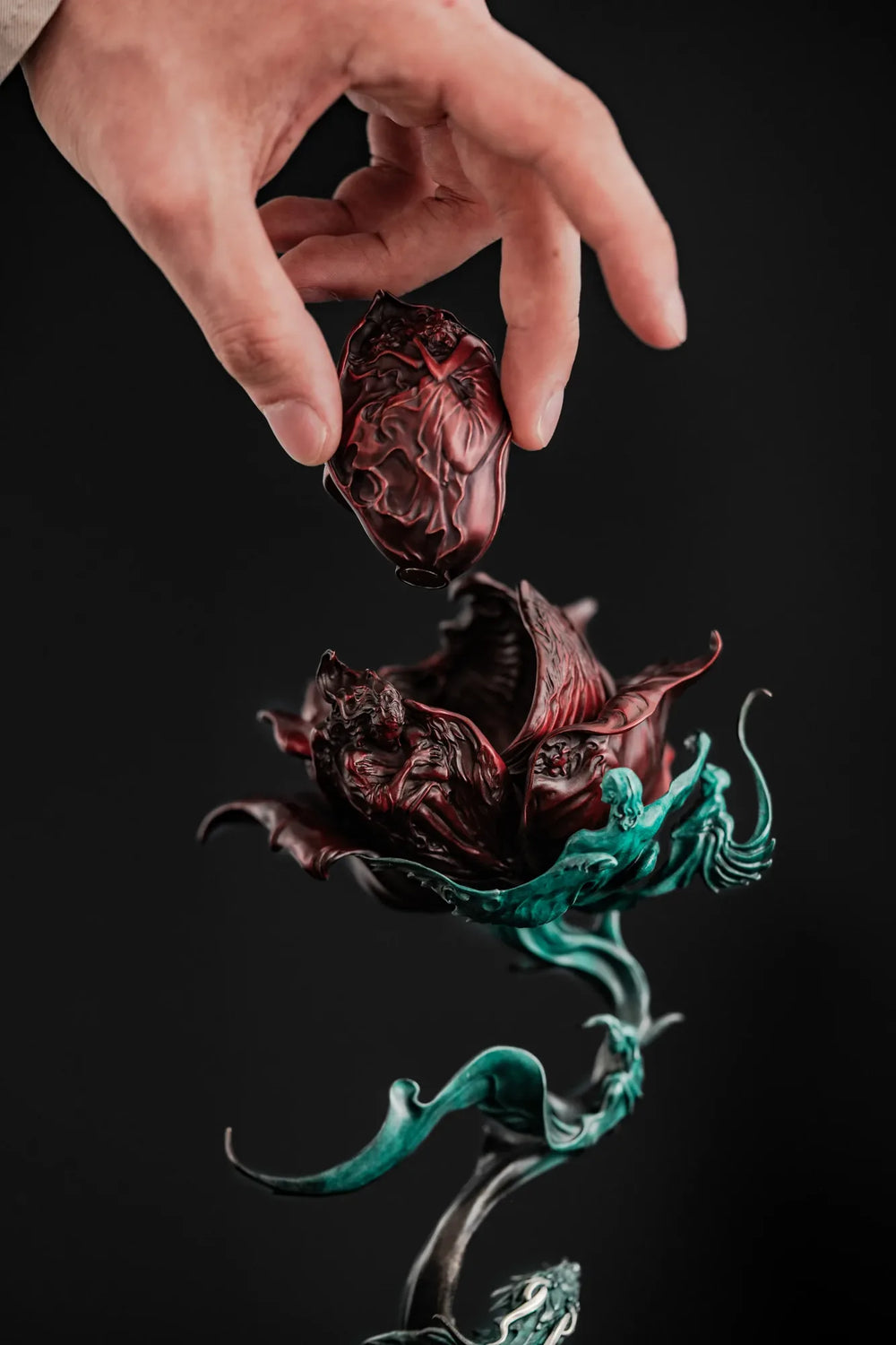 A hand lifts the removable red petal from Celestial Rose