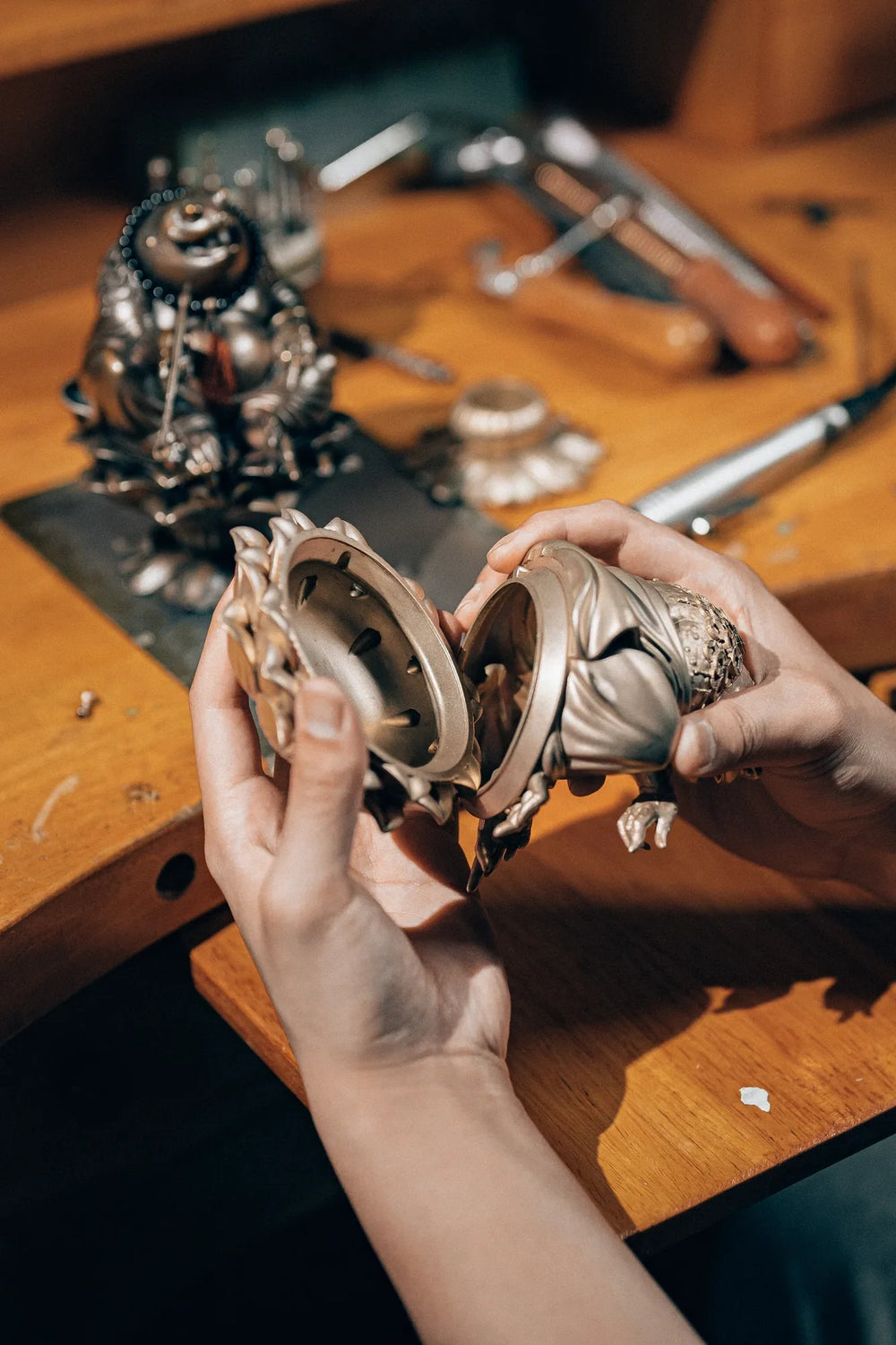 Metal components of the Maitreya Toad incense burner being assembled by hand